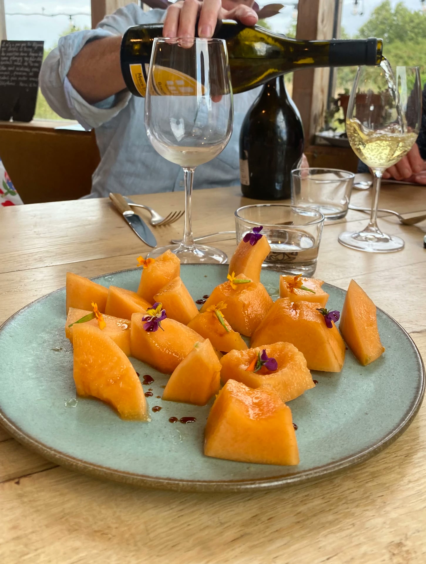 Fresh melon slices with flowers and wine being poured