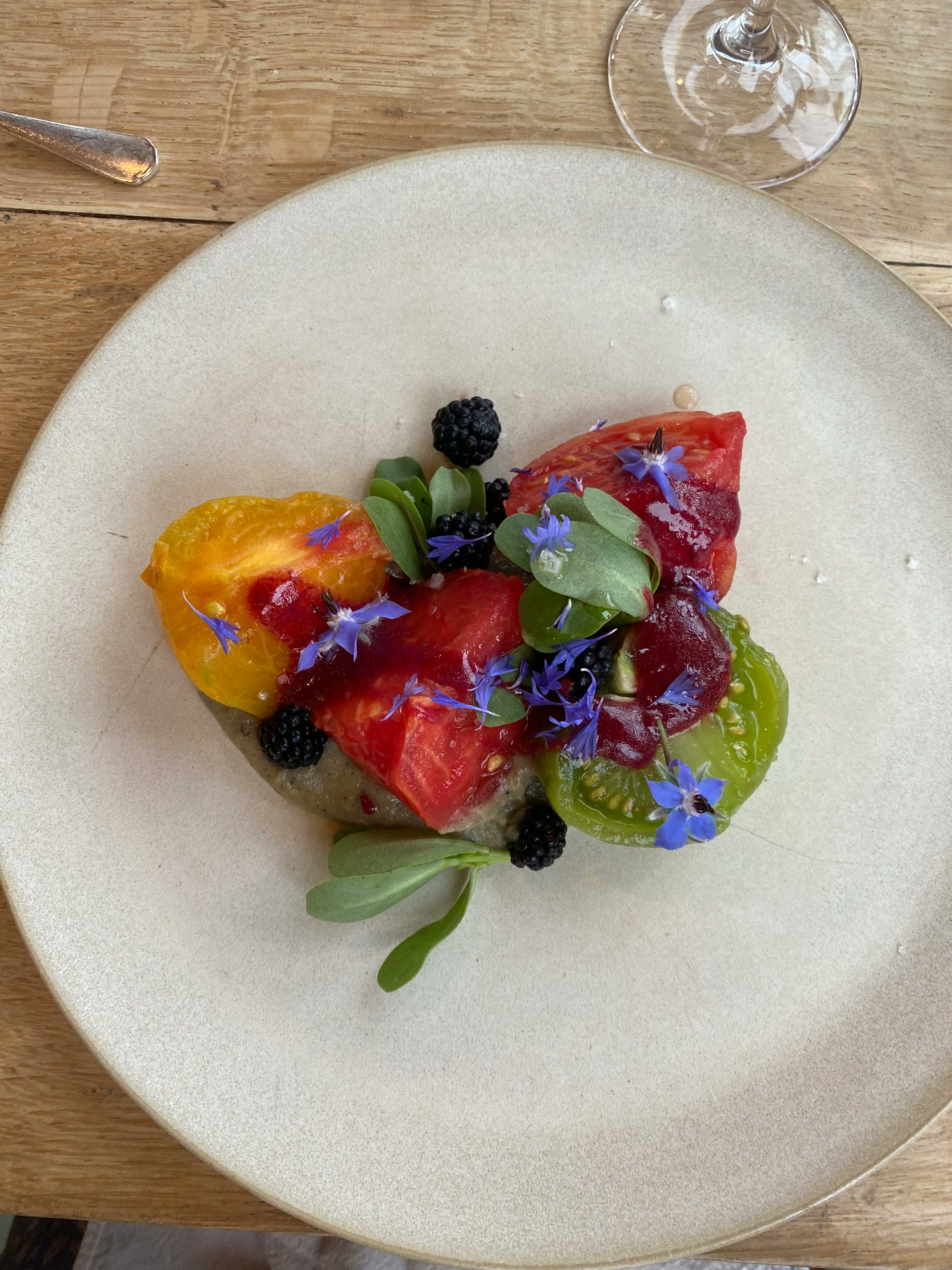A tomato salad with blackberries and edible flowers